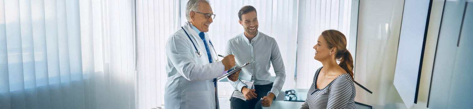 En glad läkare, tolk och patient samtalar efter undersökning.